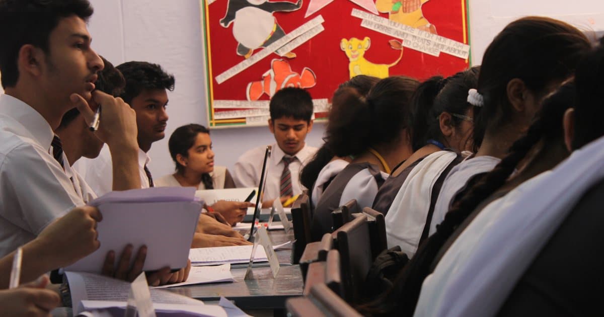 A teenage student resting his chin on his hand, deep in thought during a class discussion
