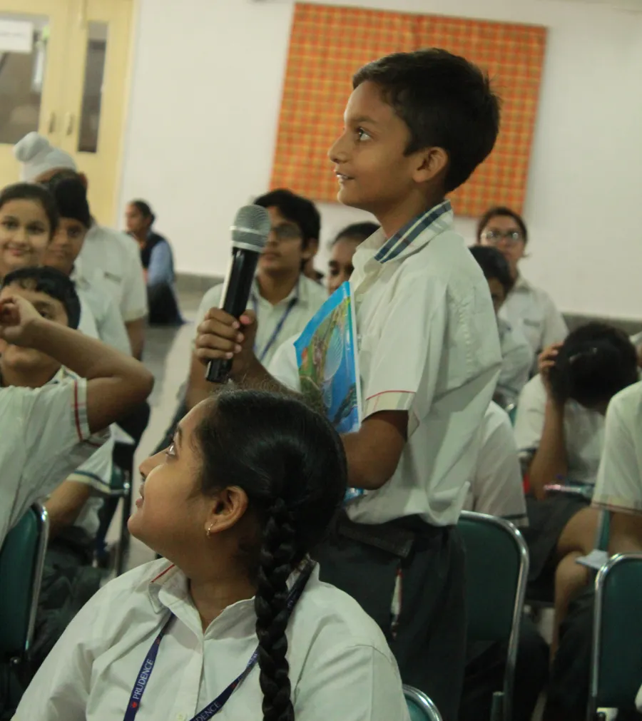 A boy asking a question in class while a girl beside him looks up and listens
