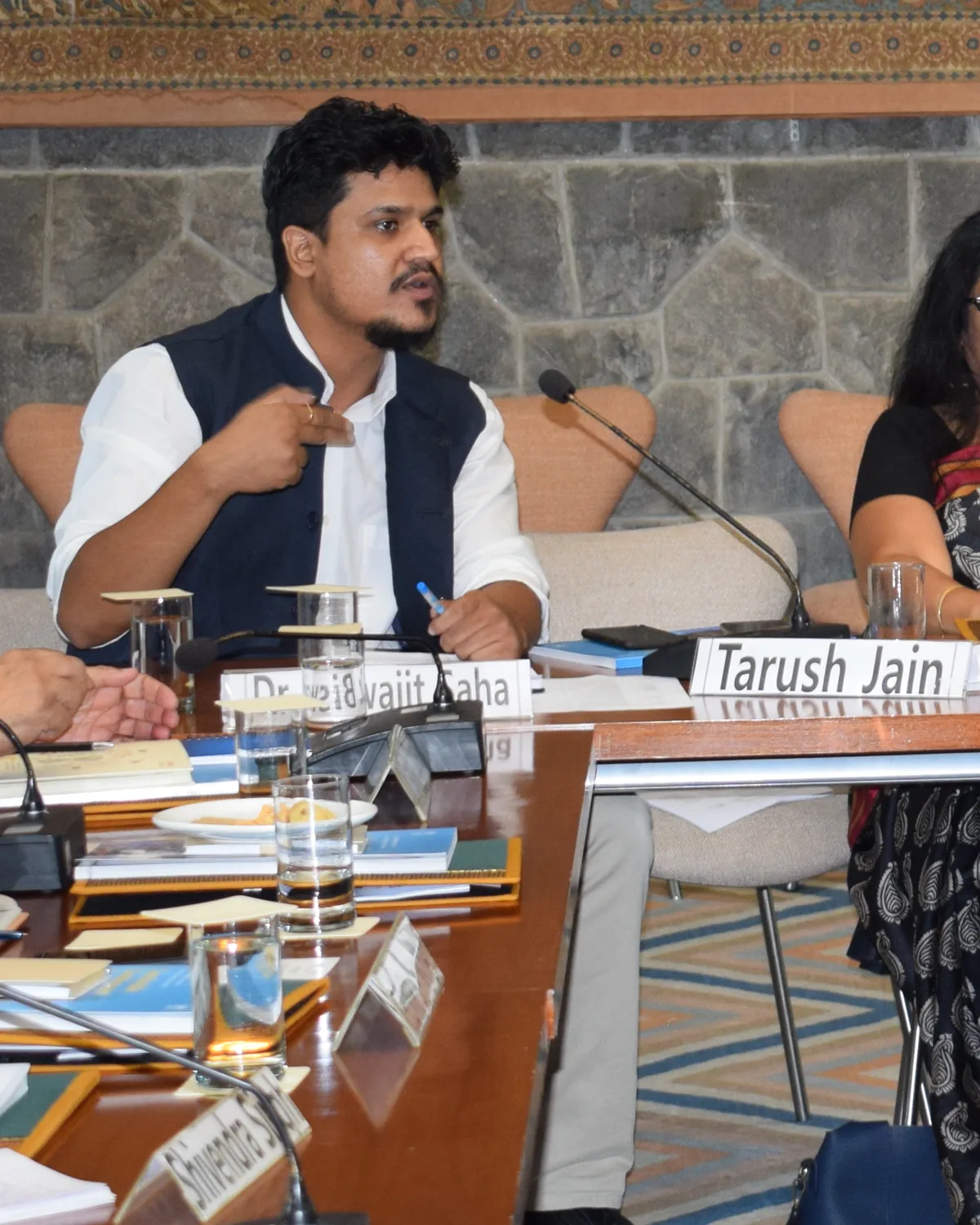 Tarush Jain speaking at the roundtable table, beside Dr. Neelam Gupta